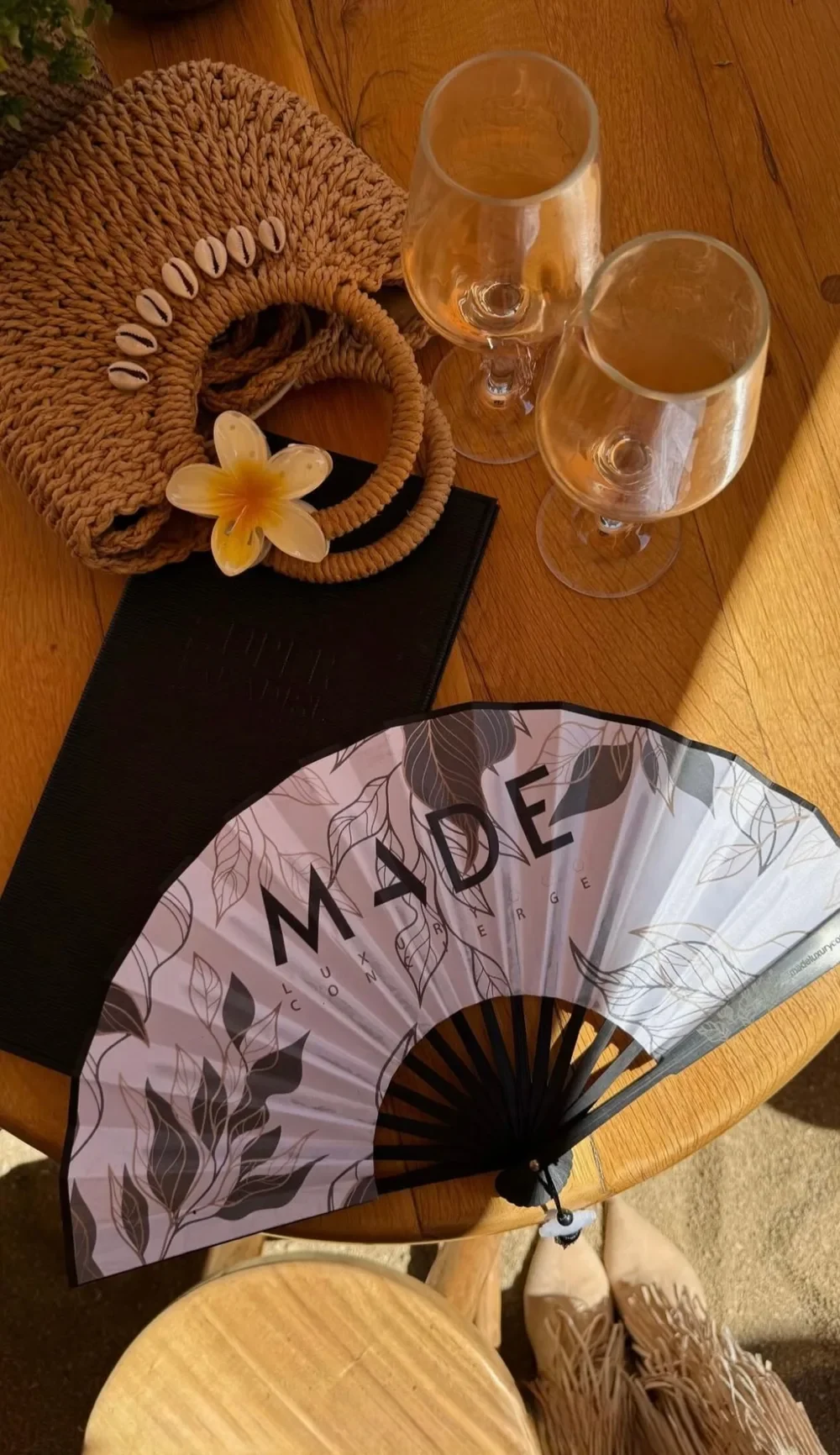 El abanico de MADE sobre una mesa de beach club en Mykonos, con dos copas de rosado